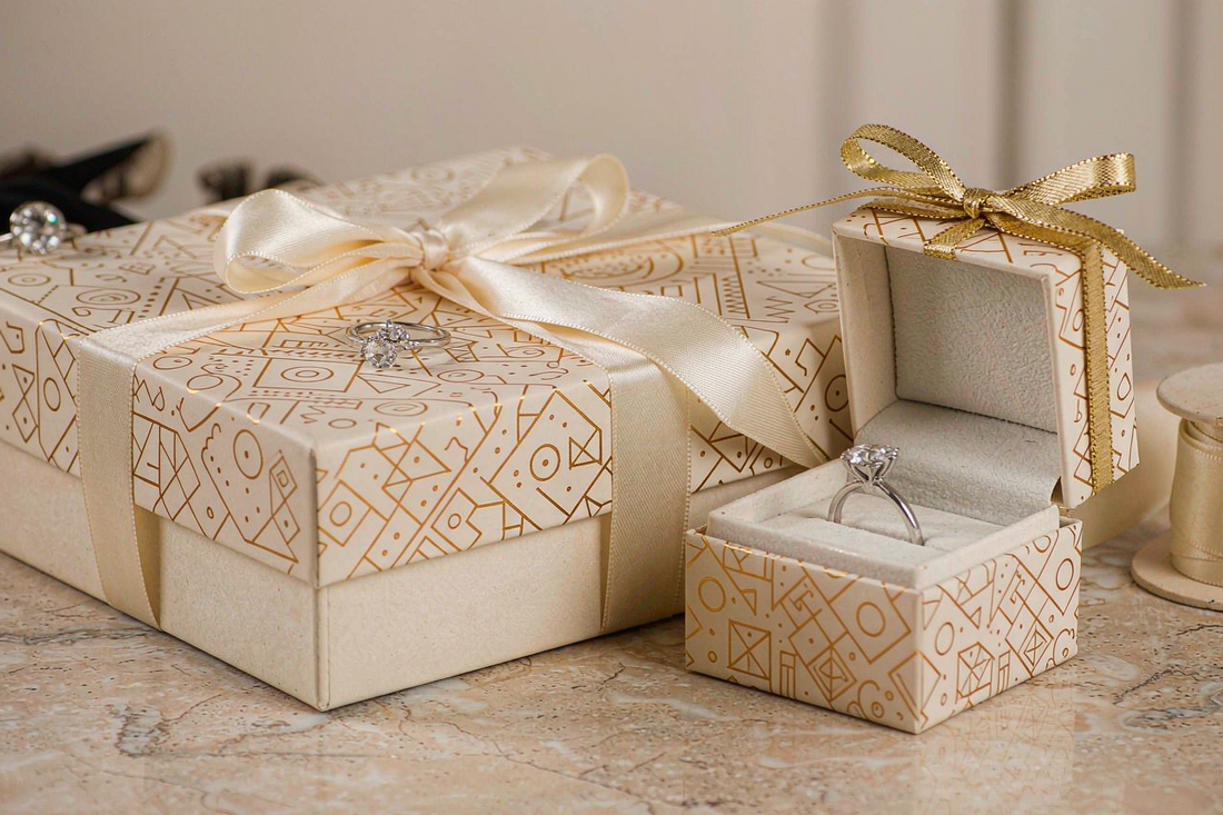elegant jewelry gift boxes with sparkling moissanite rings and cream silk ribbons on beige marble