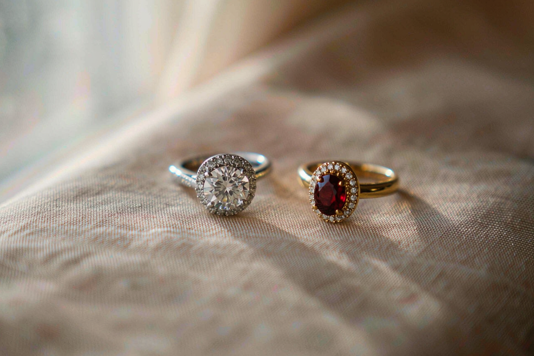 round brilliant moissanite ring and oval garnet ring placed side by side on warm beige linen fabric