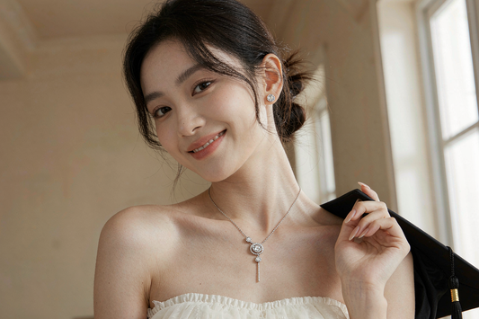 young woman graduate wearing a moissanite pendant necklace and stud earrings holding a graduation cap