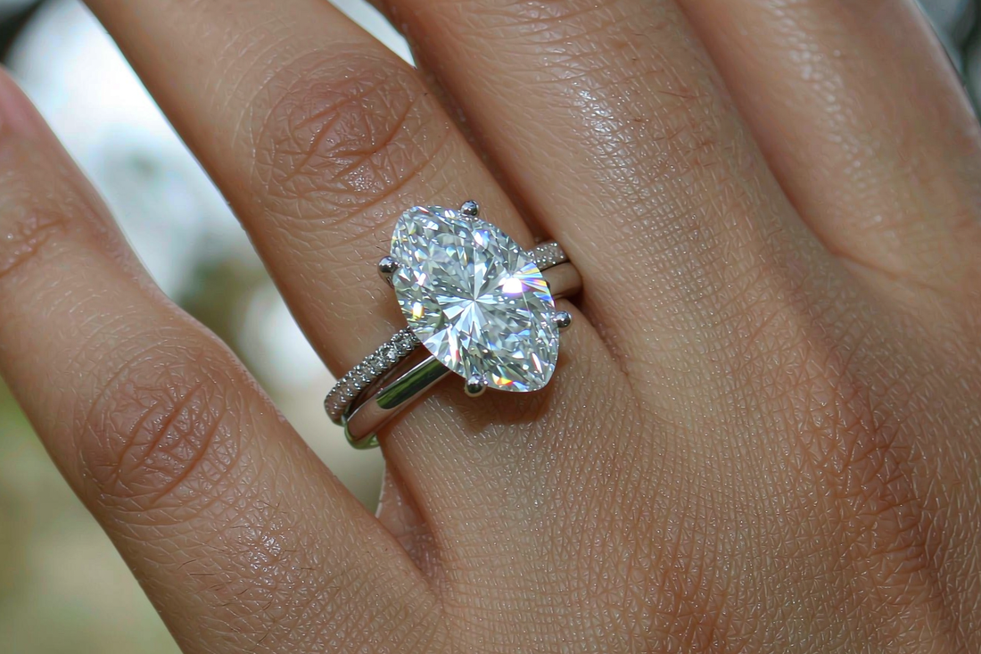 curved wedding band fitted flush against oval moissanite engagement ring on hand