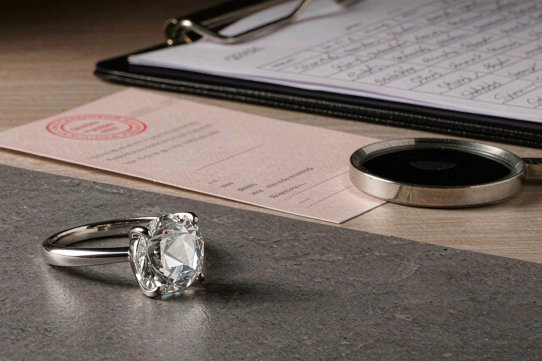 moissanite engagement ring on jeweler appraisal desk with grading certificate and loupe
