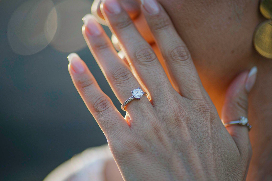 engagement photo close up of bride's hand showing moissanite solitaire ring with soft golden hour light