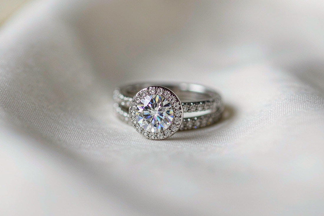 moissanite halo engagement ring and matching wedding band sitting flush together on white silk