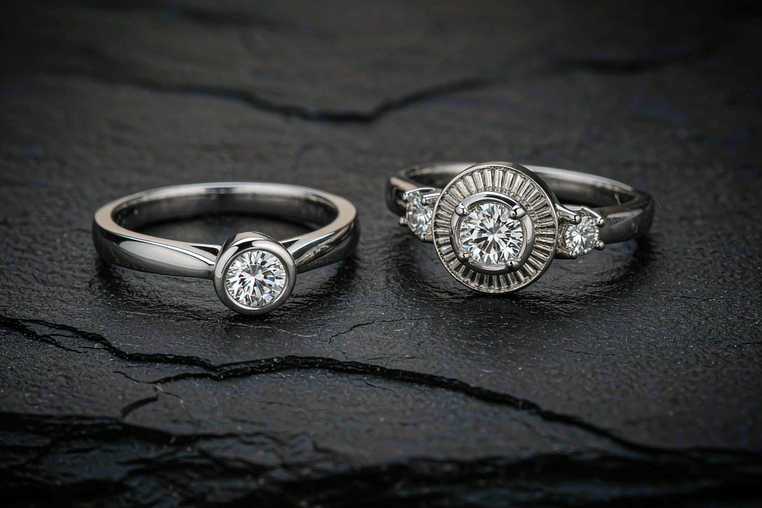 platinum and white gold moissanite rings side by side comparison on dark grey stone